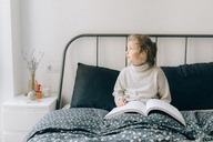 Blind woman reading a Braille book in bed