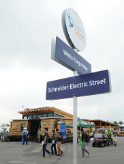 Photo of a street sign, including Wells Fargo Way, with people walking around a Solar Decathlon house beyond it.