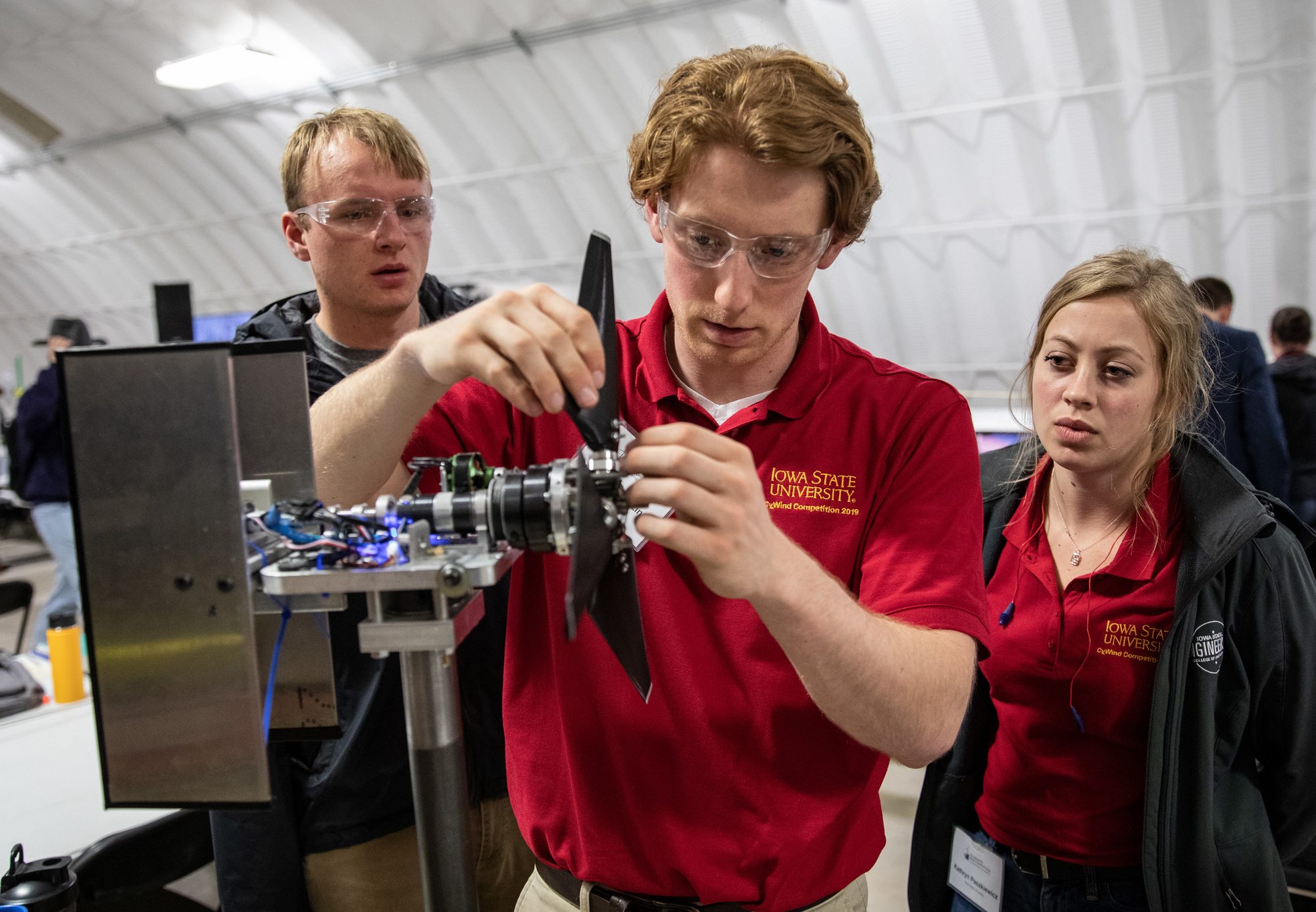 Students from Iowa State University make small adjustments to the blades of their wind turbine before a tunnel test.