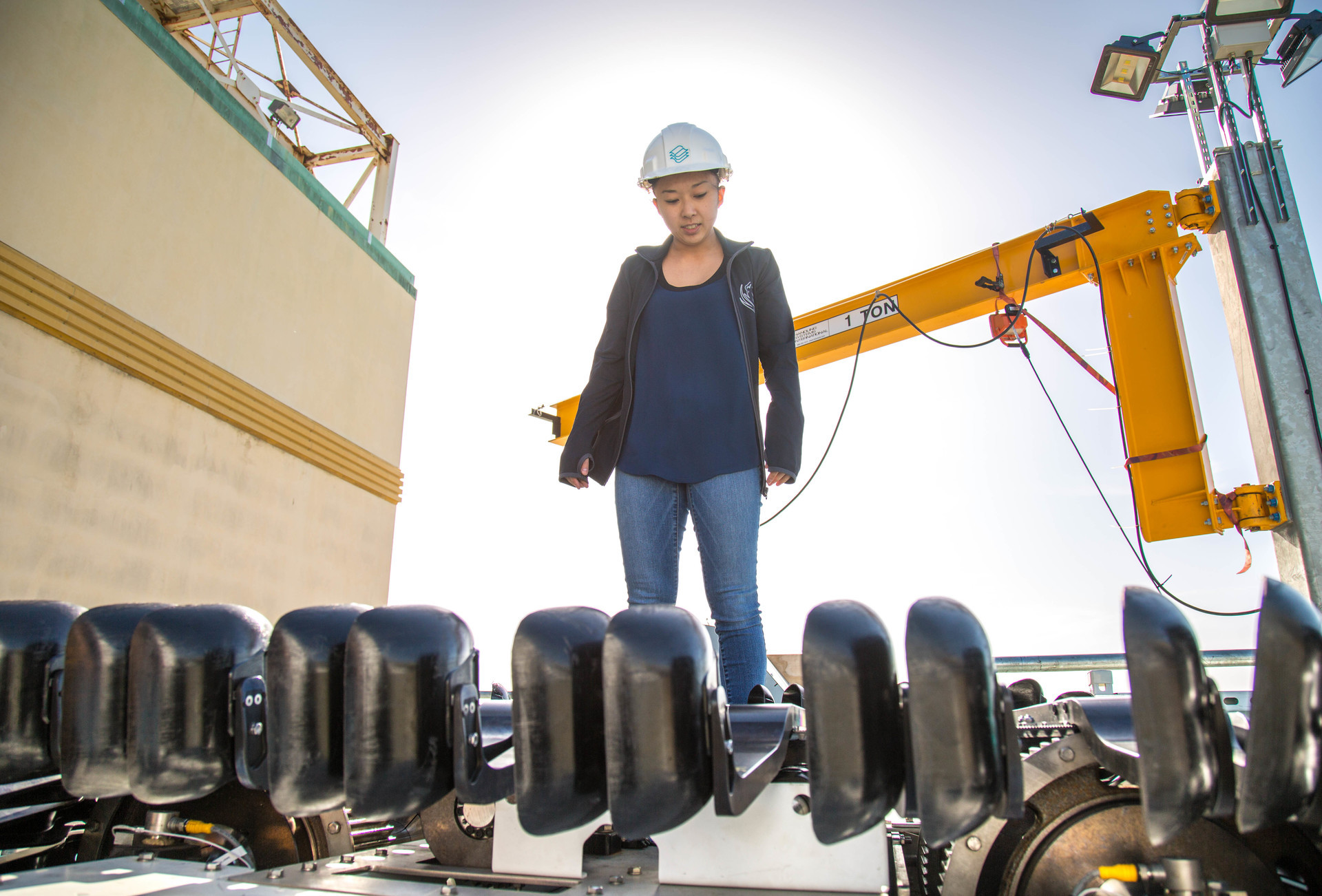 woman stands on a barge with a hardhat on.