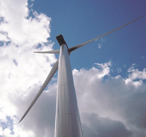 view of a wind turbine from underneath against a blue sky with some clouds.