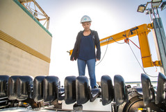 Female engineer in a hard hat standing on a boat.