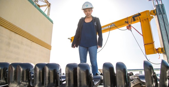 A female engineer stands on a boat working.