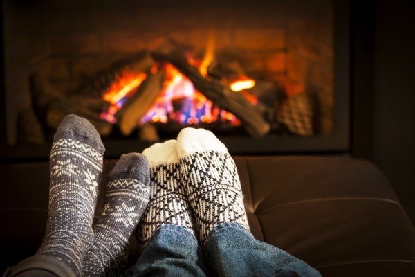 A cozy view of feet in socks in front of a fireplace