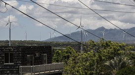 Many wind turbines across a city and mountains. 