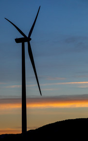 Silhouette of a wind turbine against a sunset.