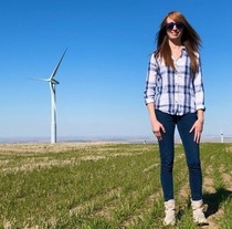 Lindsay Sheridan stands in a wind farm on a clear day.