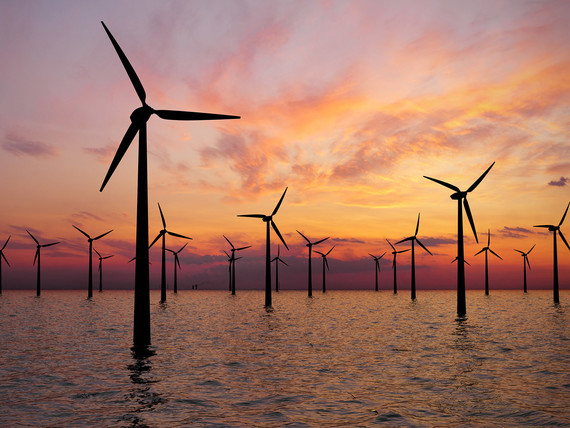 Sunset view of offshore wind turbines at sea.
