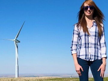 Lindsay Sheridan stands in front of a land-based wind turbine.