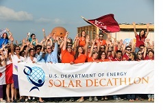 A photo from a past Solar Decathlon event, with a crowd of people holding a Solar Decathlon banner.