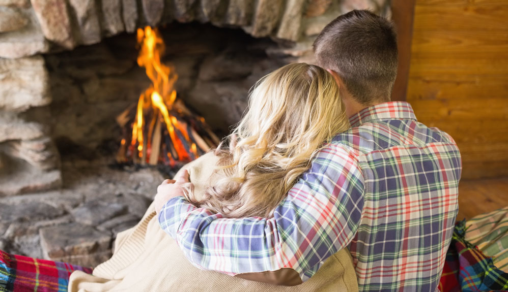 A couple sitting next to a fireplace