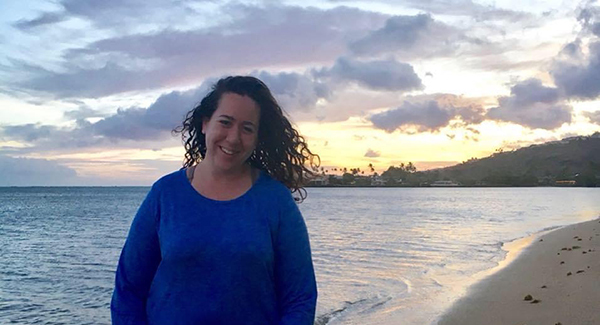 Nina Joffe smiles on a beach at sunset.
