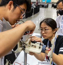 Two students adjust a model wind turbine. 
