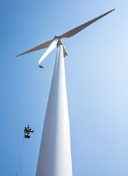 Workers hang from a wind turbine.