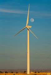 A full moon behind a wind turbine.