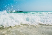 A wave crashes on a sunny beach