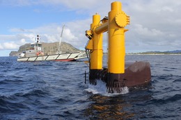 Marine energy device deployed at sea, with boat in the background
