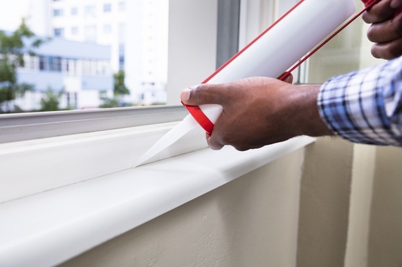 Close-up of a person adding caulking around a window frame