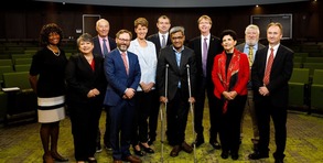 A group of people posing together on a stage in an auditorium