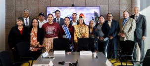A group of people, some in cultural outfits, standing at the end of a conference room.