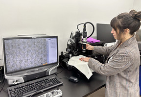 A person looking at an image on a screen next to a microscope