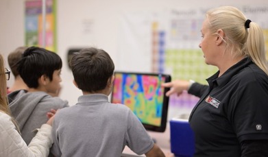 Utah FORGE’s Gosia Skowron discusses thermal characteristics while displaying a heat map on a computer screen with a small groups of students.