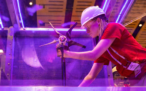 A student in a hard hat adjusts a model wind turbine