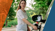 Woman charging vehicle on rural road. 