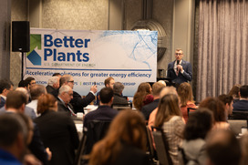 People watching a speaker with microphone next to a Better Plants banner