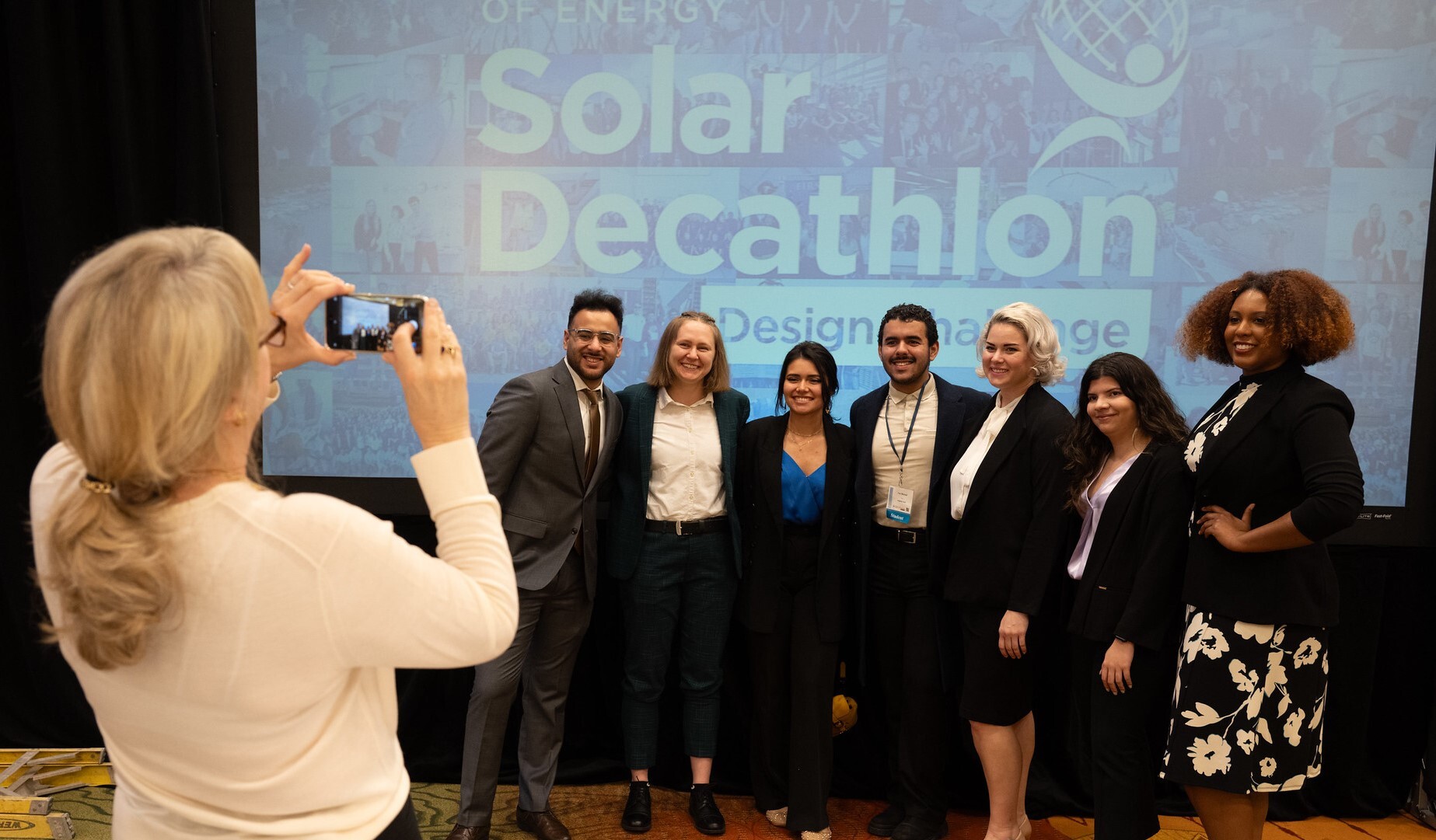 A photo of a Solar Decathlon team in front a banner that reads 