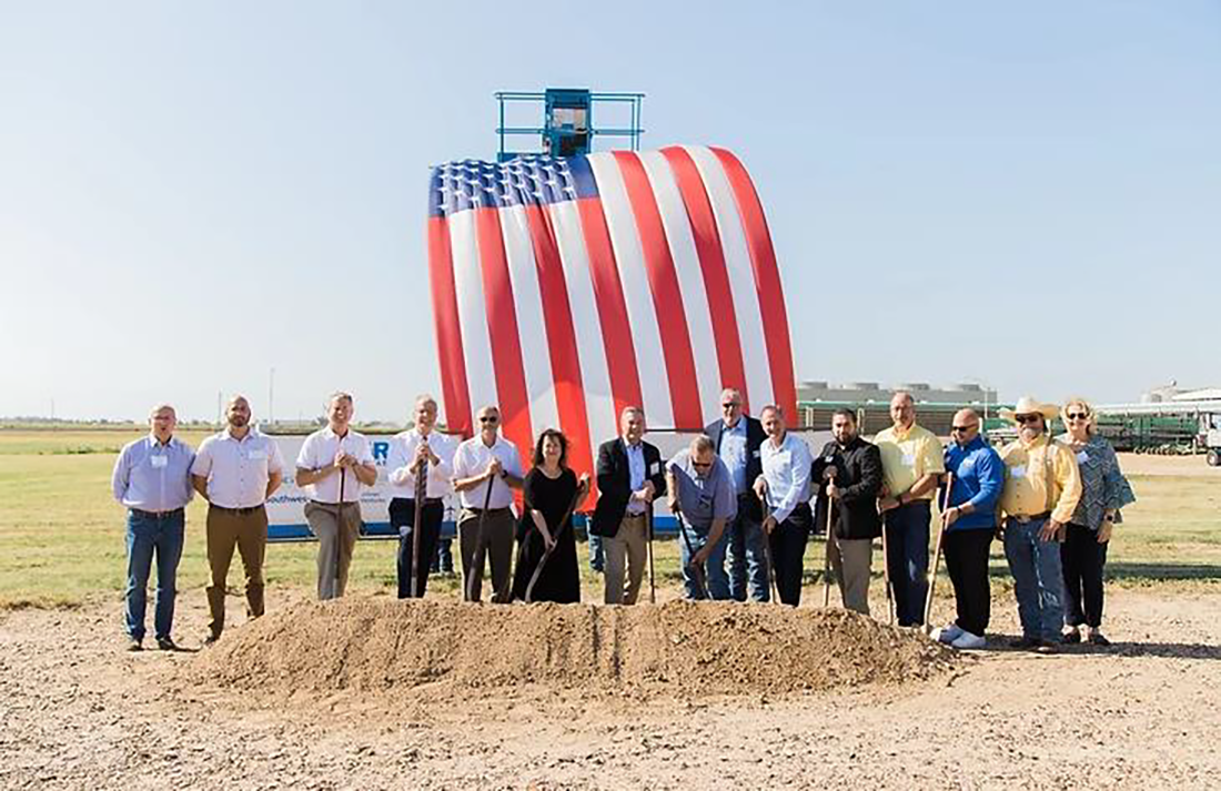 Breaking ground at site with US flag in background