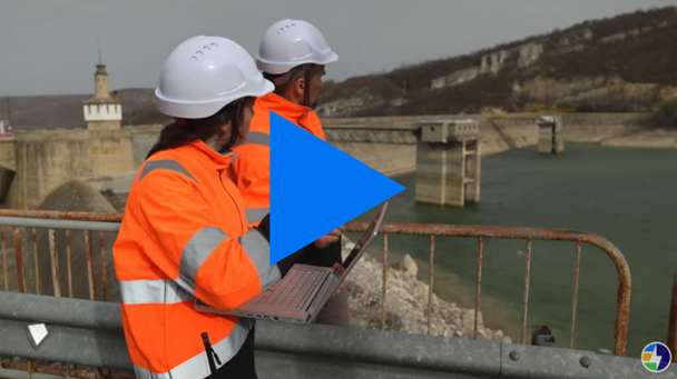 Photo of two people standing on a hydropower dam