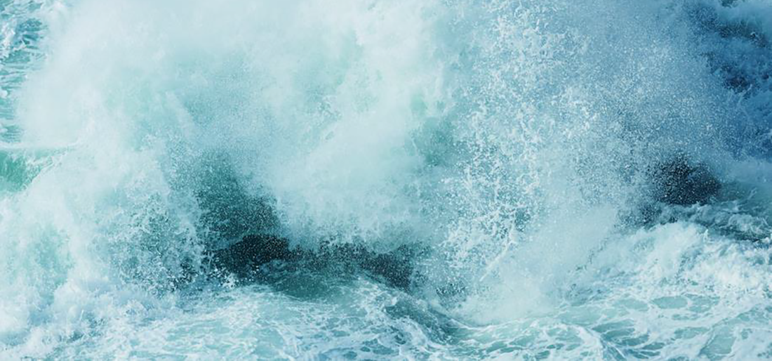 Ocean waves near Newport, Oregon, crash and spray foam.