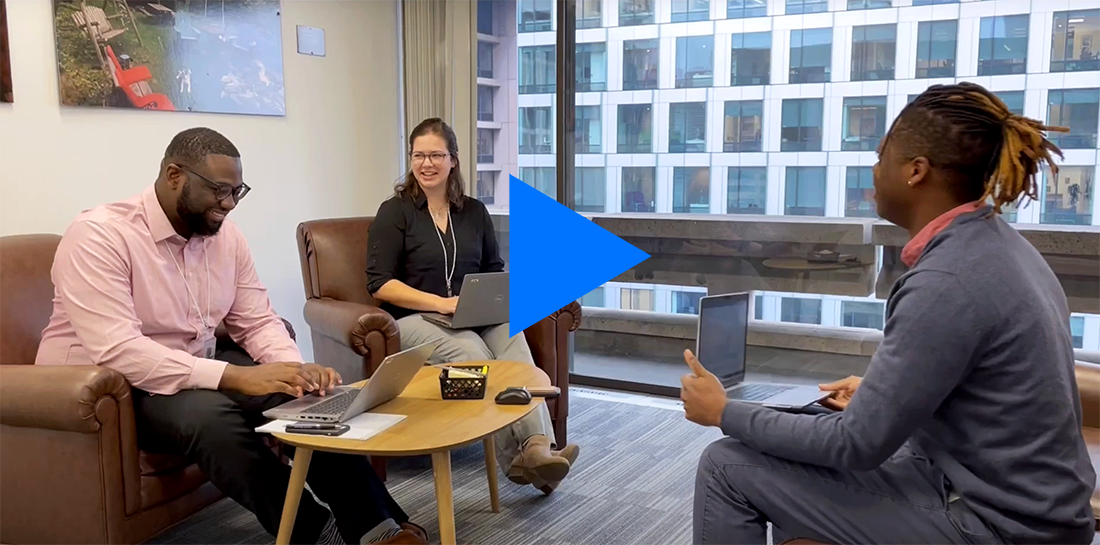 Three solar fellows happily sit in chairs around a table with laptops out.