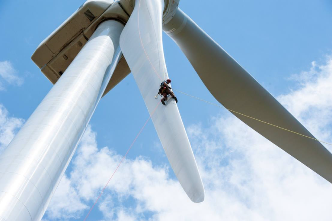 A worker perches on a wind turbine blade. 