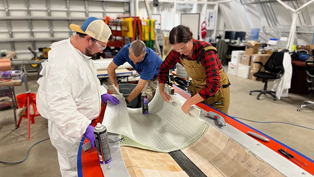 NREL team glues together a 9-meter wind turbine blade made with fiberglass composites and a balsawood core.