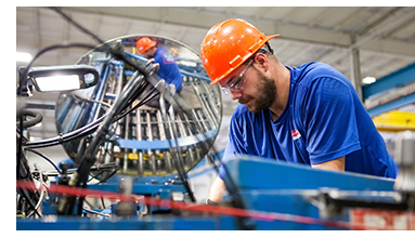 Worker wearing hard hat and safety goggles in manufacturing plant