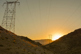 Sun rising over the mountains with powerlines in the distance