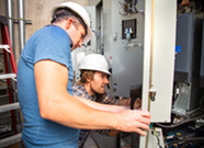 Several workers examine electrical components 