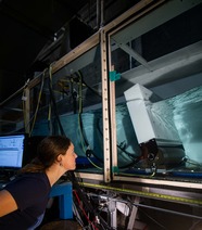 A scientist closely examines a wave tank as they prepare for a test