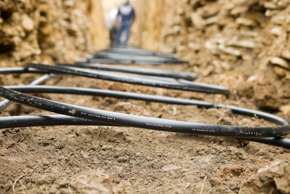 Workers laying geothermal coils in a trench. Credit: iStock