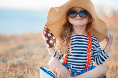 Child with big hat and sunglasses in the sun