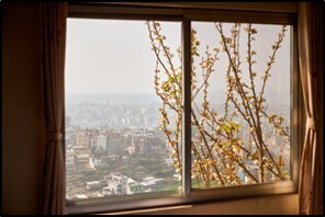 View through a window showing tree branches in the foreground and a distant cityscape outside.