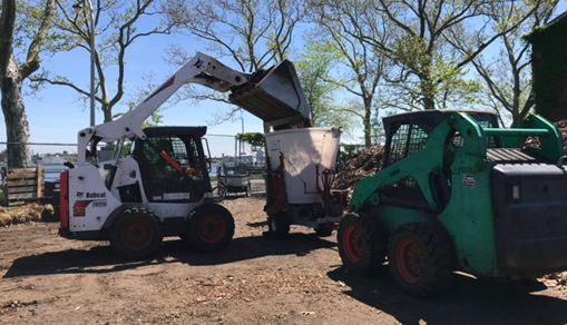 two ulitity vehicles work on a community composting site
