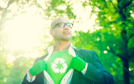 man with a recycling symbol on his shirt standing in the forest