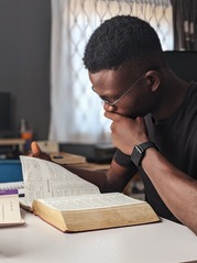 man closely reading a book and studying