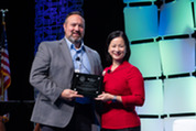 Anthony Lomelin (left) accepts an Acquisition Excellence Award on behalf of his team from Christine Harada (left)