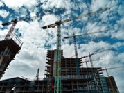 Various cranes next to multiple high rise buildings in a construction project