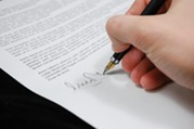 zoom in photo of a hand signing a contract on paper