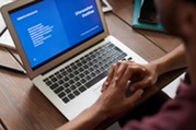 Person using a laptop on a desk taking an online course